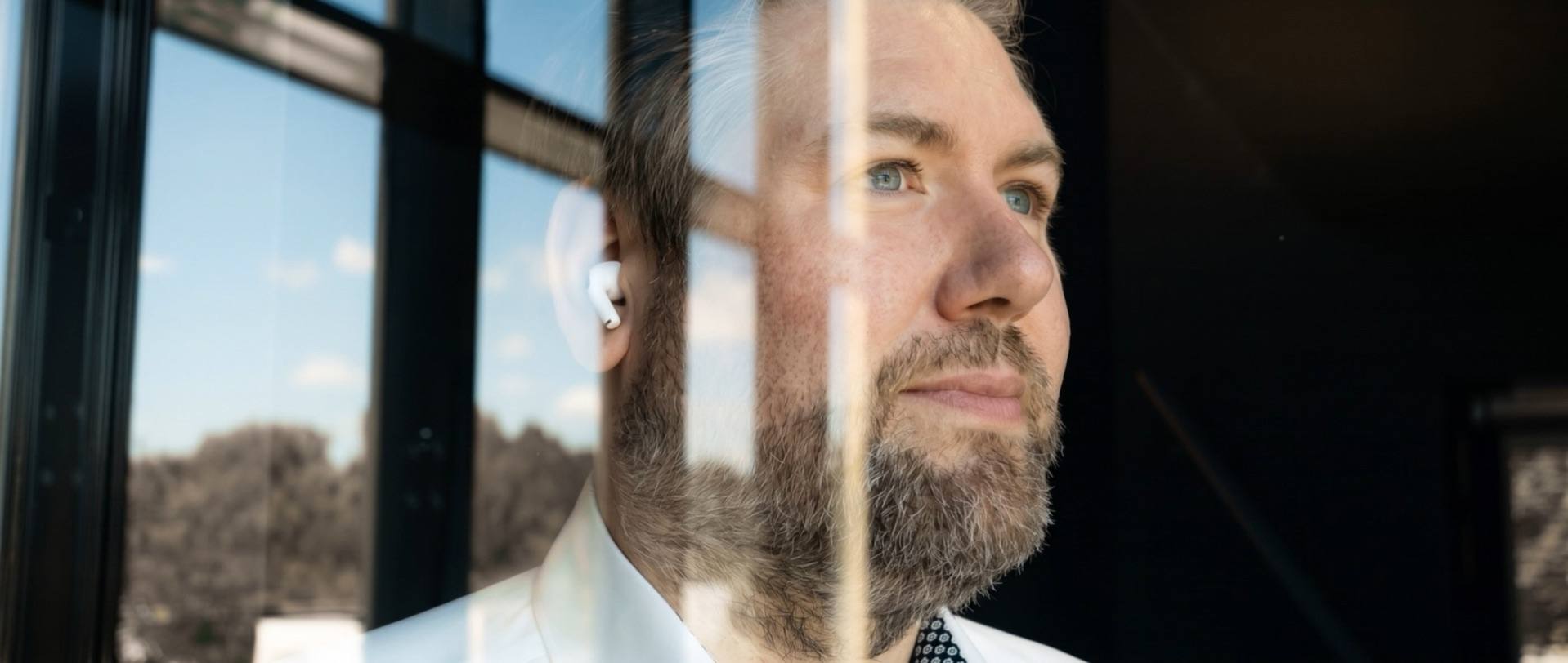 Christian Finke, Inhaber von Finke Praxismarketing, blickt durch ein Fenster nach draußen (KI-animiert)