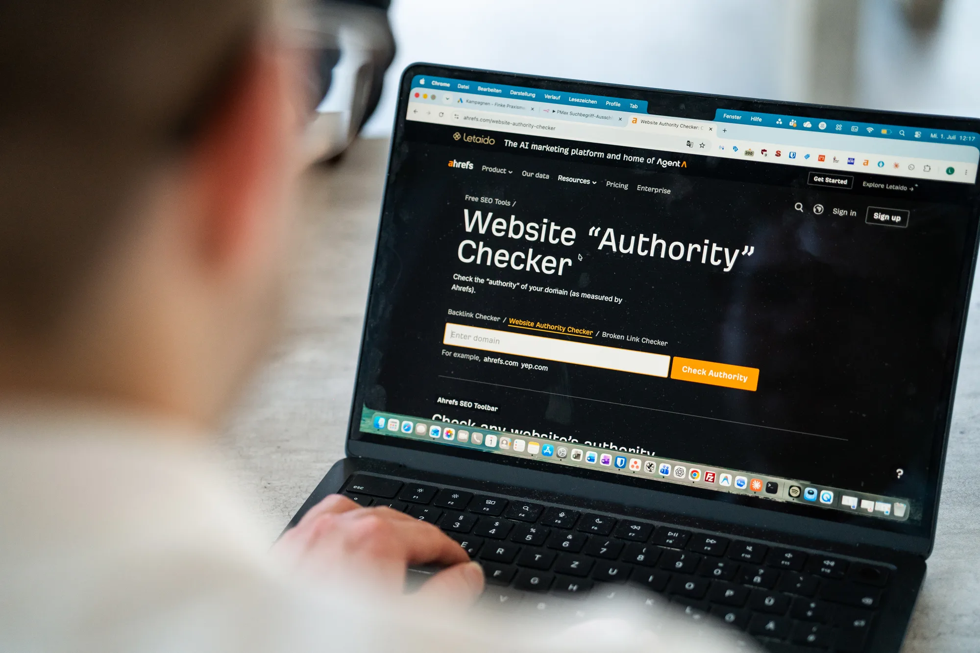 Laptop mit geöffnetem SEO-Werkzeug, im Vordergrund unscharf eine Person an der Tastatur