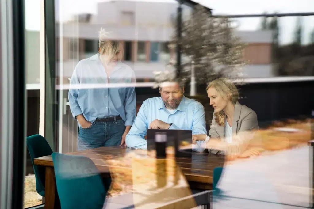 Besprechung im Team von Finke Praxismarketing, durch eine Glasscheibe fotografiert